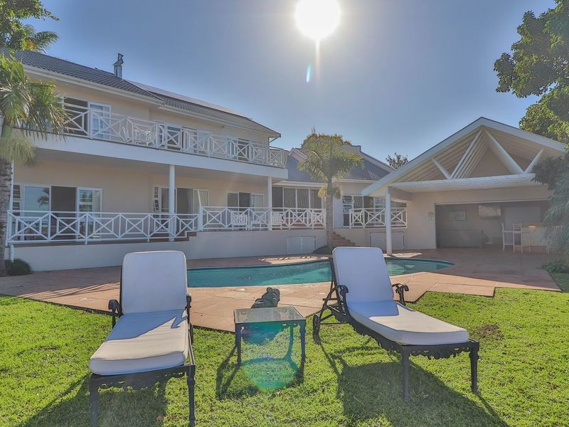 Rear view of the property featuring a swimming pool, tiled patio area, and a two-story building with balcony access.