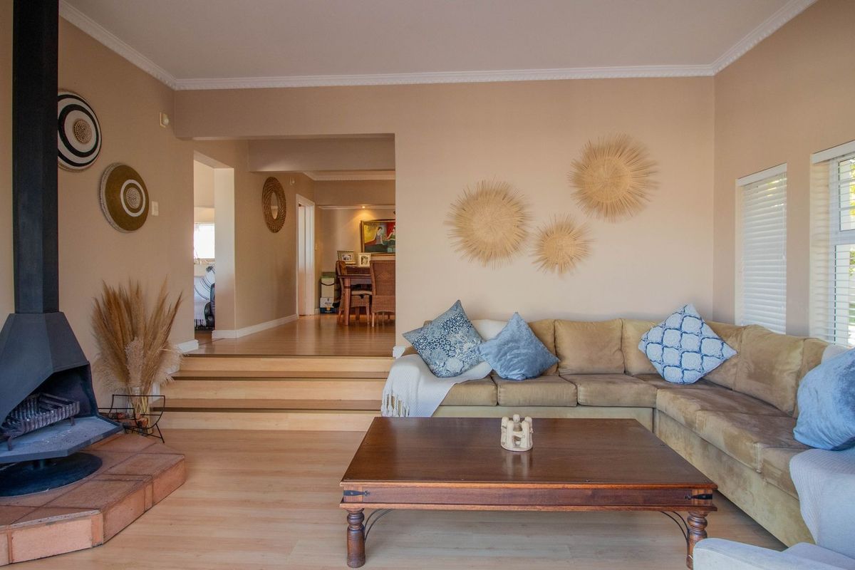 A comfortable living room featuring a prominent freestanding fireplace, light laminate flooring, and a raised platform leading to the adjacent dining area.