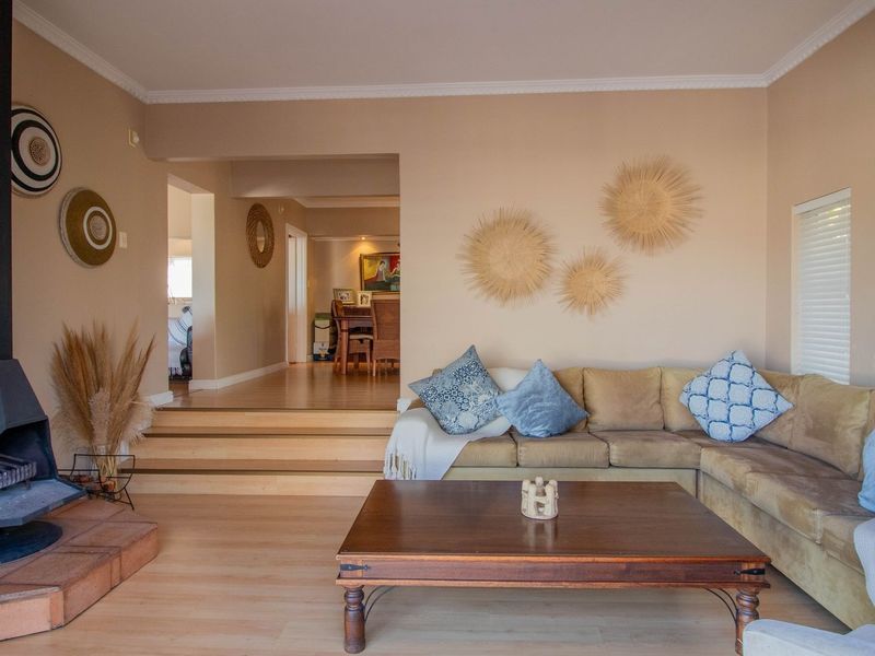 A comfortable living room featuring a prominent freestanding fireplace, light laminate flooring, and a raised platform leading to the adjacent dining area.