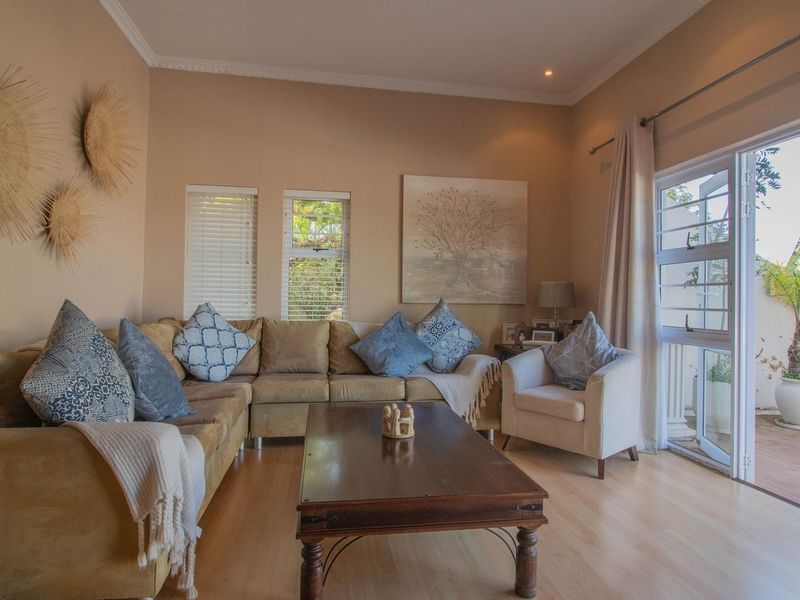 A comfortable living room featuring laminate flooring, recessed lighting, and large sliding doors that provide direct access to an outdoor patio area.