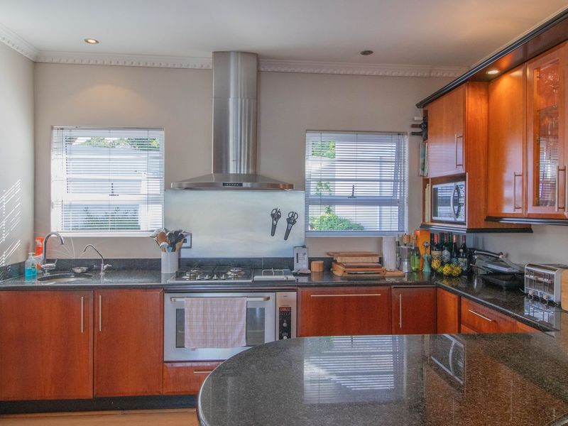 A well-appointed kitchen featuring granite countertops, wooden cabinetry, a stainless steel extractor fan, and a built-in oven with a gas hob.