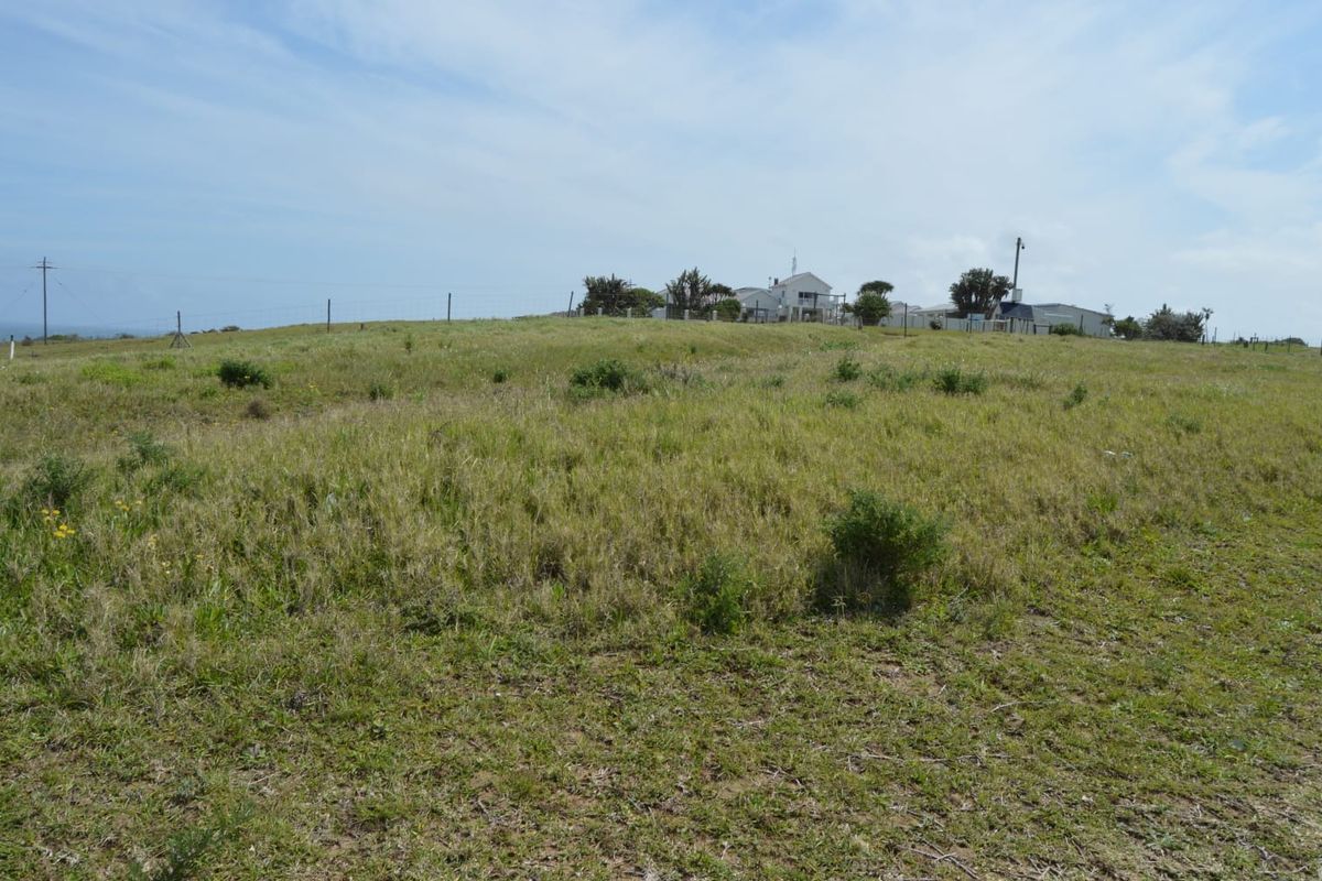 A view of the vacant residential land featuring natural grass coverage, perimeter wire fencing, and a utility pole on the property boundary.