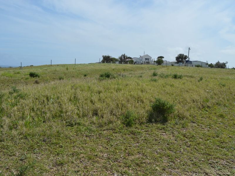 A view of the vacant residential land featuring natural grass coverage, perimeter wire fencing, and a utility pole on the property boundary.