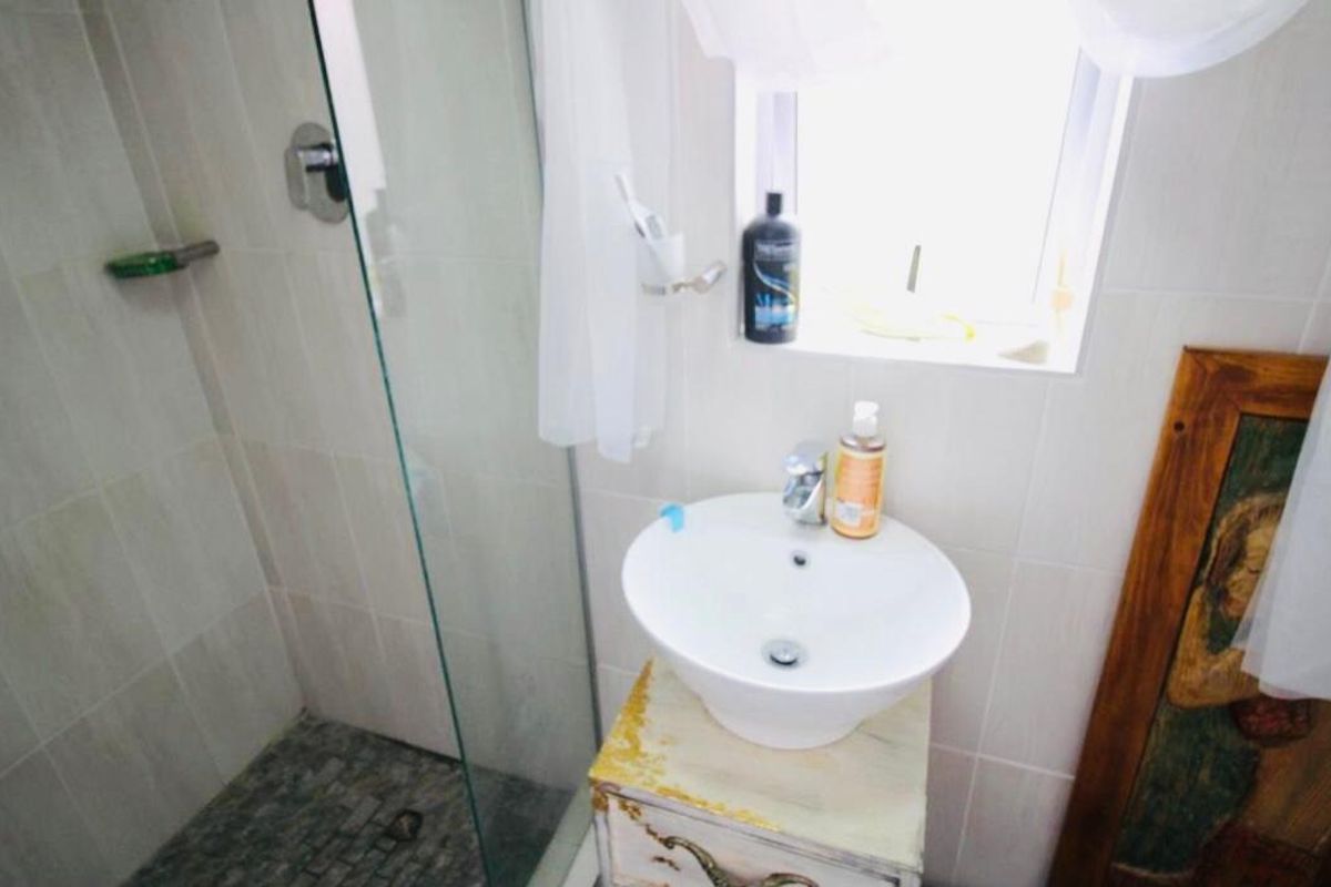 A compact bathroom featuring a glass-enclosed shower with pebble flooring and a modern vessel sink vanity.