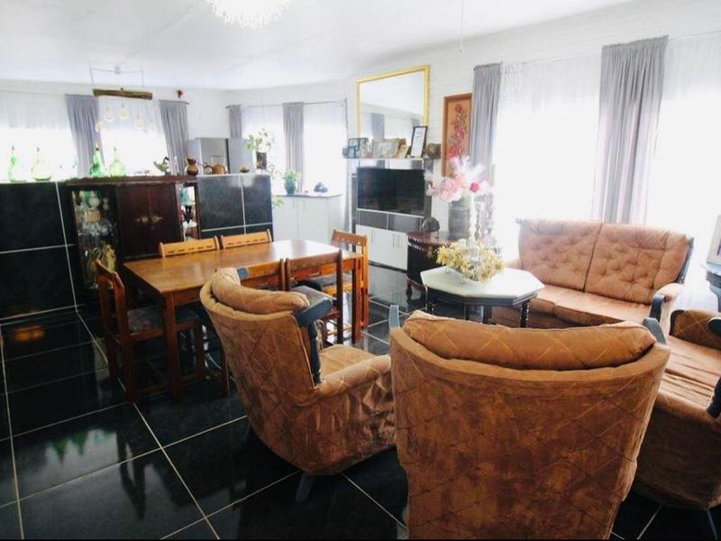 Spacious open-plan living and dining area featuring dark tiled flooring and integrated cabinetry, offering a versatile layout for family living.