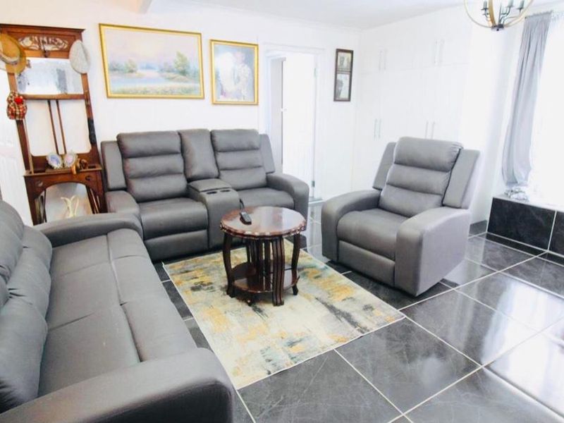 A living room featuring dark tiled flooring and built-in storage cupboards, offering a functional space for relaxation.