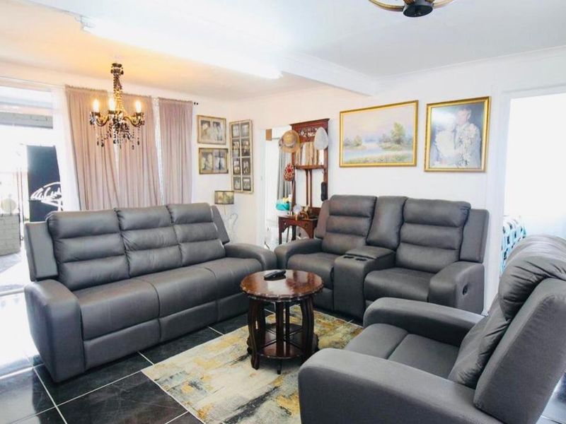 A living room featuring dark tiled flooring and a central ceiling light fixture, providing a functional and well-lit space.