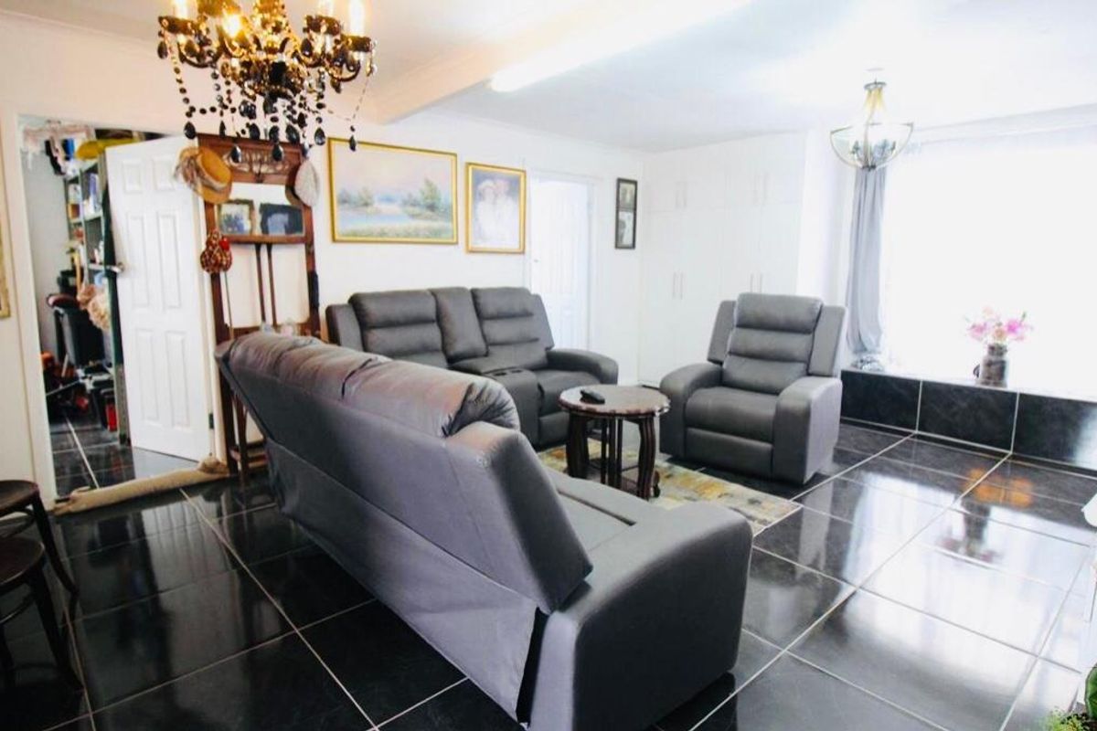 Spacious living room featuring dark polished floor tiles, built-in storage cupboards, and decorative chandelier lighting.