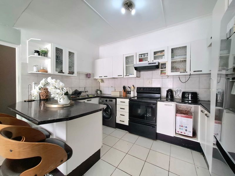 A functional kitchen featuring white cabinetry, granite countertops, a breakfast nook, and tiled flooring, providing a practical layout for daily cooking and dining.