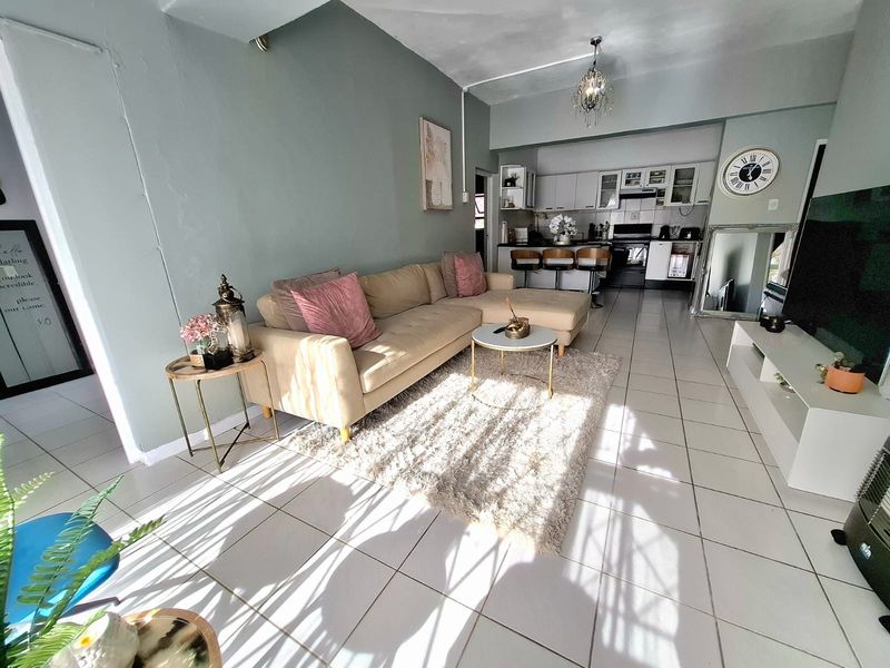 Open-plan living area featuring tiled flooring, a modern kitchen with built-in cabinetry, and a breakfast counter, creating a functional and connected living space.