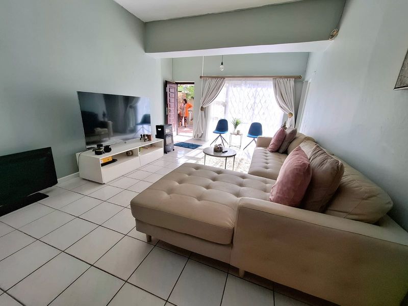 A bright living room featuring tiled flooring and a sliding glass door providing access to the exterior.