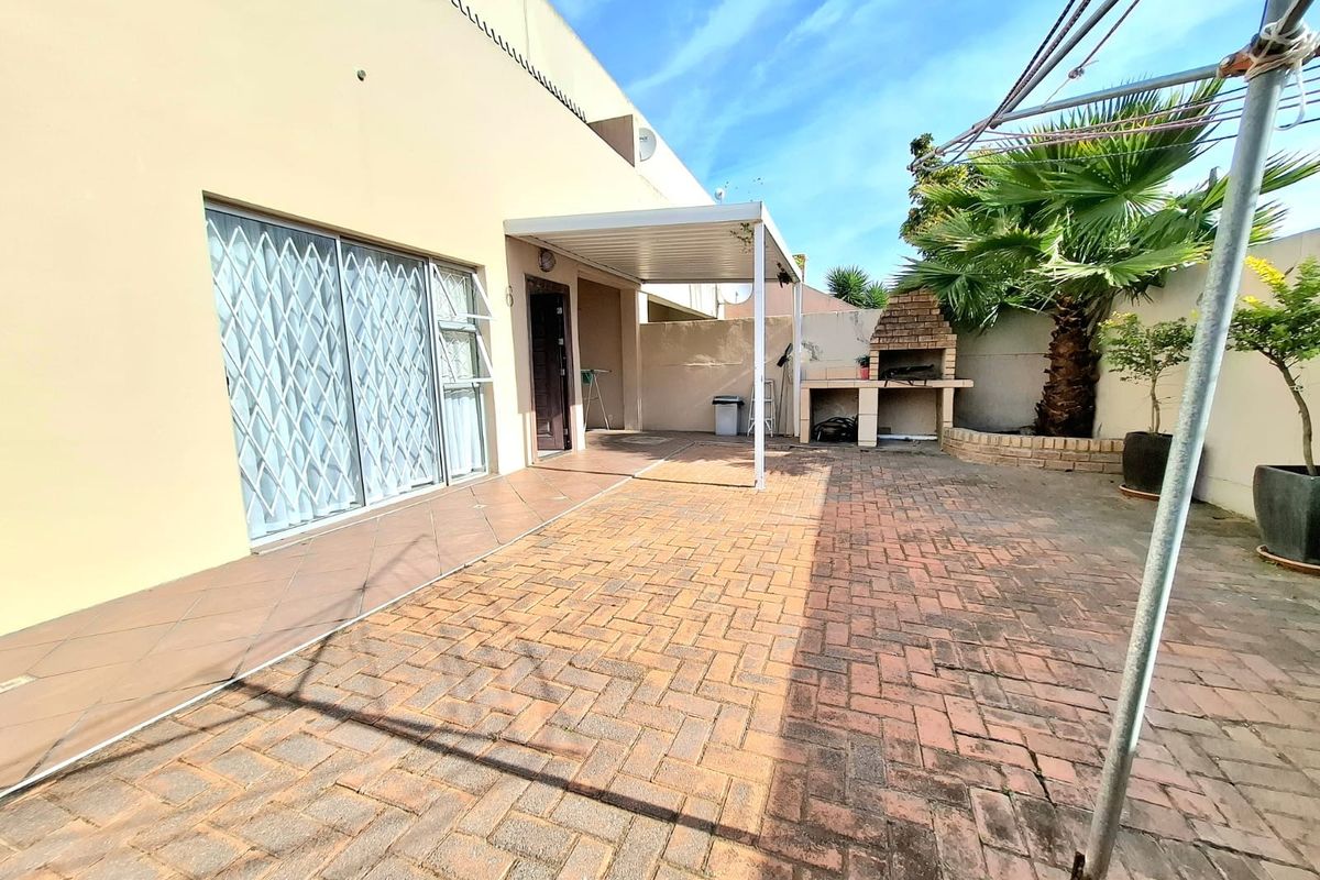Rear exterior area featuring a brick-paved patio, a covered section, and a built-in braai, providing a functional outdoor entertainment space.