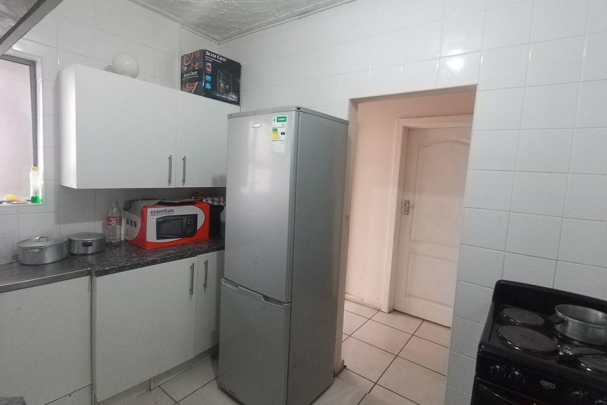 A functional kitchen featuring white cabinetry, tiled walls, and tiled flooring, providing a practical layout for daily meal preparation.