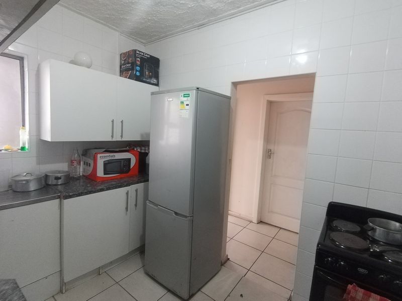 A functional kitchen featuring white cabinetry, tiled walls, and tiled flooring, providing a practical layout for daily meal preparation.
