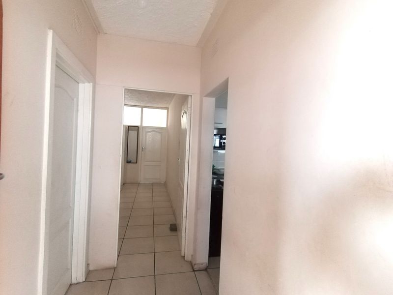 A functional hallway featuring tiled flooring and access to multiple rooms, showing signs of wear on the walls.