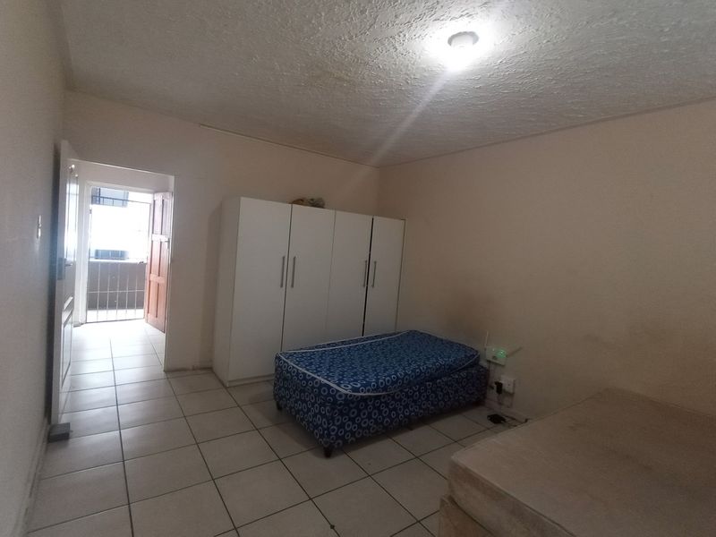 A bedroom featuring tiled flooring and a built-in wardrobe, with direct access to an outdoor balcony area.