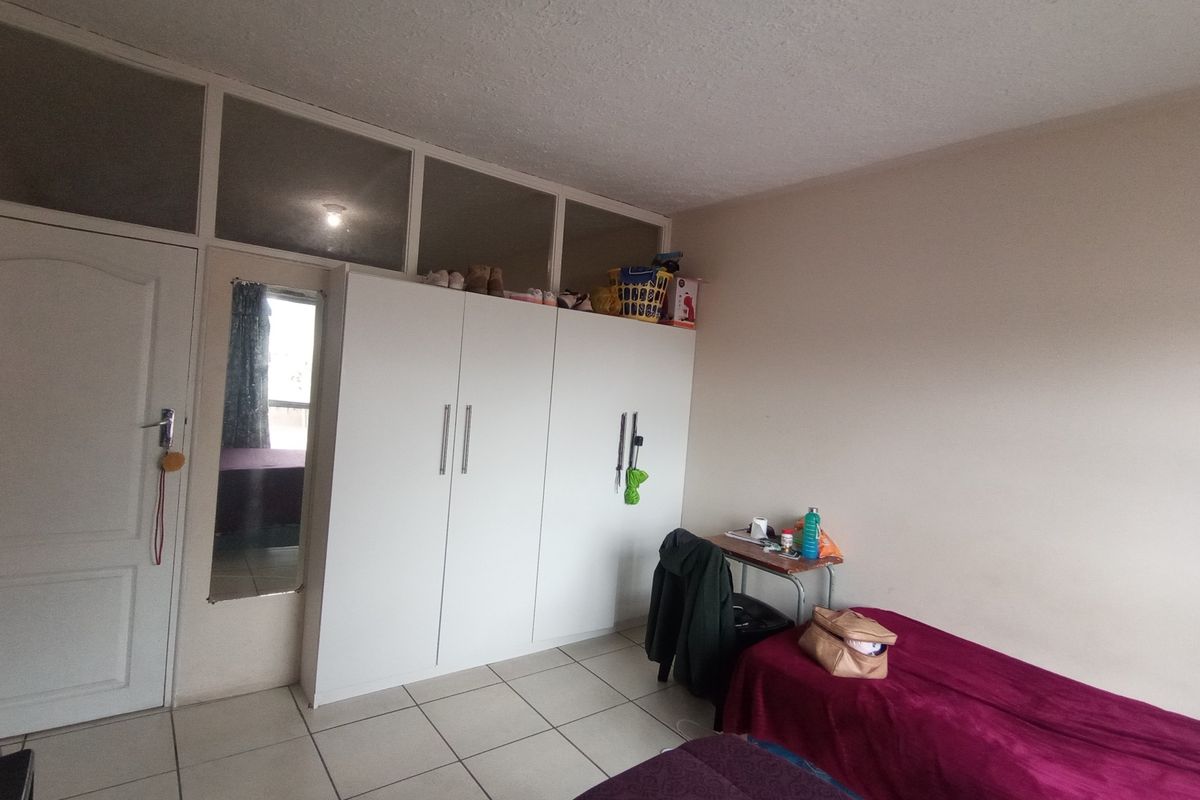 A bedroom featuring tiled flooring, a built-in wardrobe with overhead storage, and transom windows above the door.