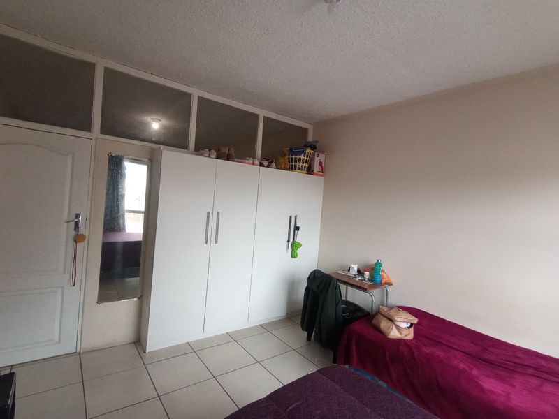A bedroom featuring tiled flooring, a built-in wardrobe with overhead storage, and transom windows above the door.