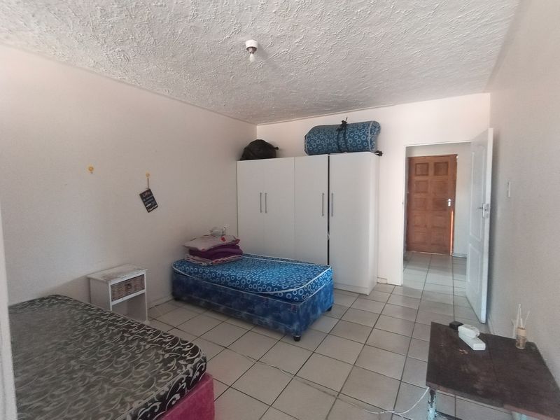 A bedroom featuring tiled flooring, a built-in wardrobe, and a textured ceiling, requiring cosmetic updates to improve its overall condition and appeal.