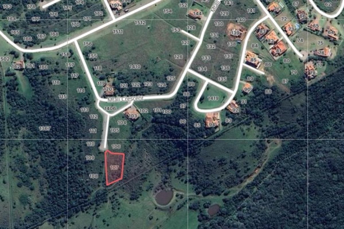 Aerial view of a vacant residential land plot highlighted in red, situated within a developed estate with established road access.