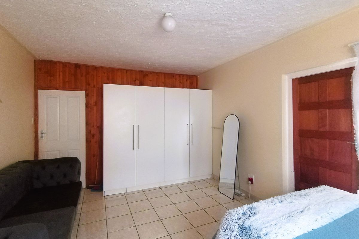Bedroom featuring tiled flooring, built-in white wardrobes, and decorative wooden wall paneling.