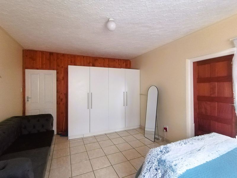 Bedroom featuring tiled flooring, built-in white wardrobes, and decorative wooden wall paneling.
