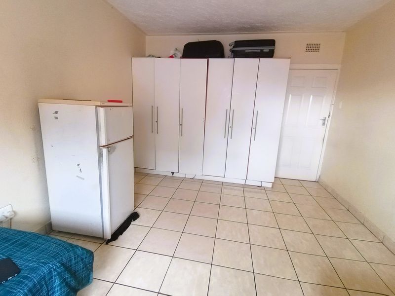 A bedroom featuring tiled flooring and built-in cupboards, offering functional storage space in a neutral setting.