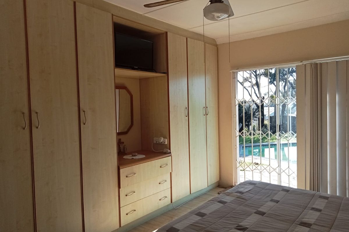 Bedroom featuring extensive built-in cabinetry, a ceiling fan, and a sliding glass door providing direct access to the pool area.