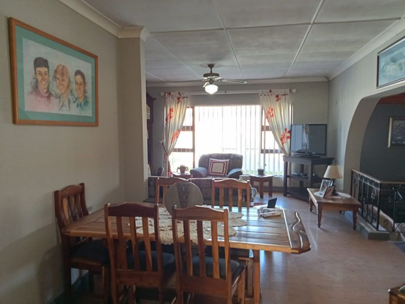 Open plan living and dining area featuring tiled flooring, coved ceilings, and a ceiling fan, with access to a staircase with wrought iron balustrade.