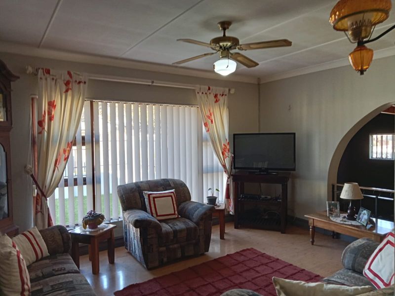 A living room featuring laminate flooring, a ceiling fan, and a distinctive arched entryway, providing a functional and traditional living space.