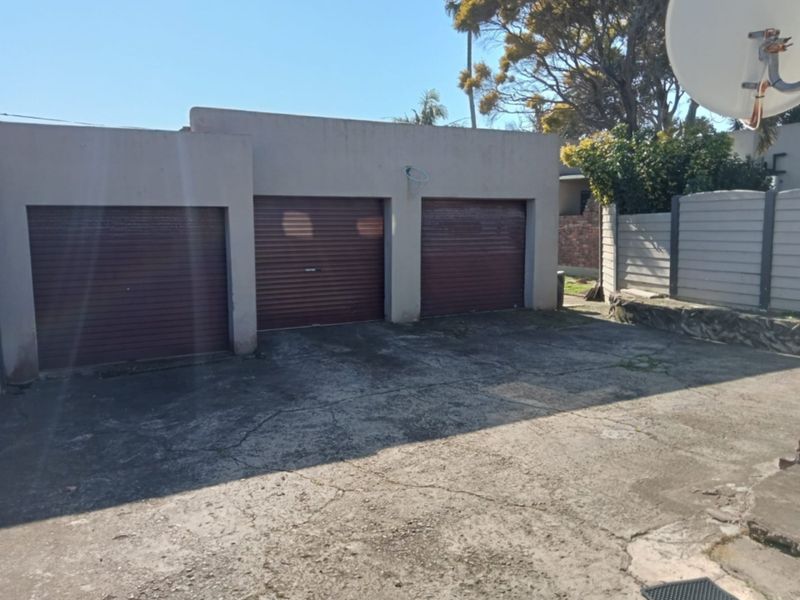 A triple garage structure with roller doors and a large concrete driveway area.