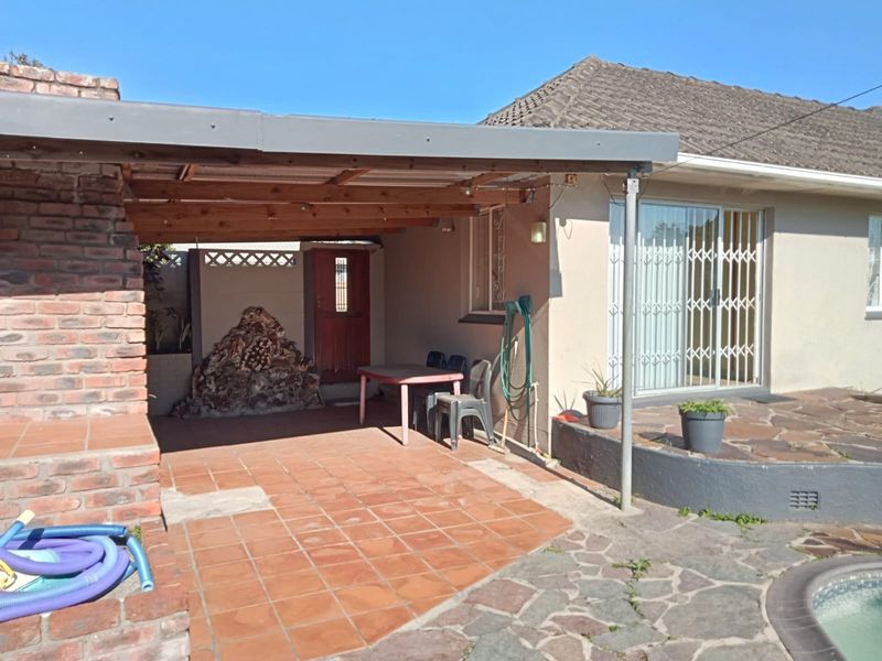 Covered outdoor patio area featuring a built-in brick braai, tiled flooring, and direct access to the home via a sliding security door.