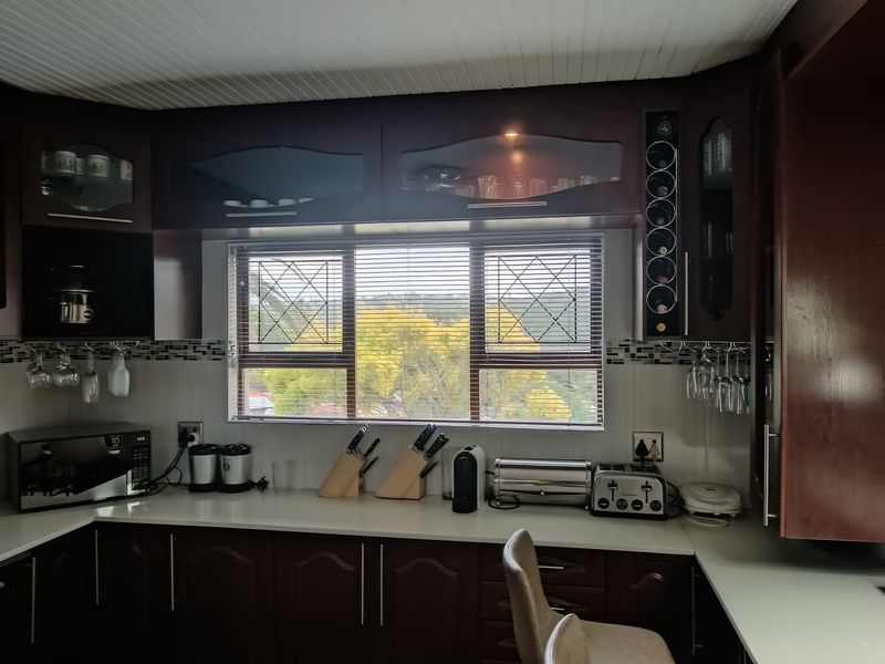 A functional kitchen featuring dark wood cabinetry, a tiled backsplash, and a window with a view, providing ample storage and counter space.