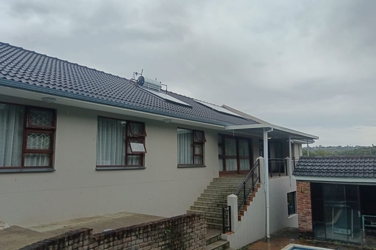 Rear exterior view of the house featuring a tiled roof with solar water heating, a concrete staircase, and a swimming pool area.