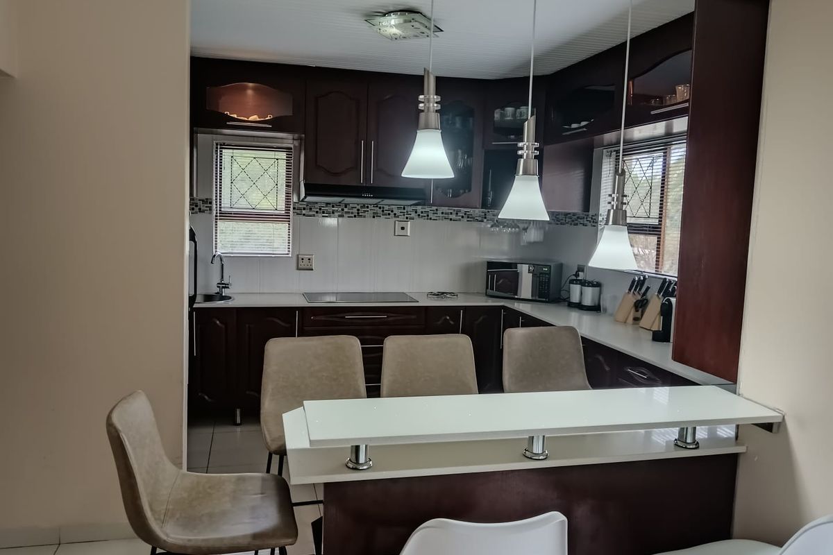 A functional kitchen featuring dark wood cabinetry, a breakfast bar with pendant lighting, and a tiled backsplash, offering a practical layout for daily use.