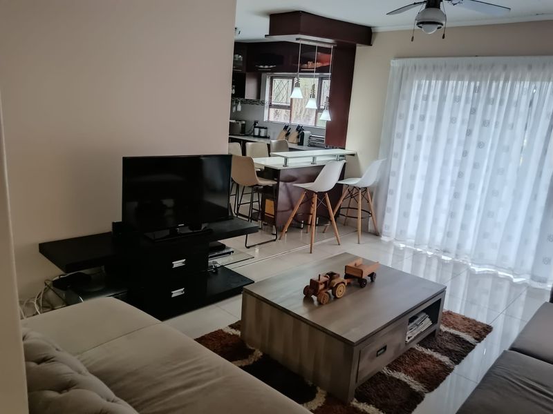 Open plan living area featuring tiled floors, a breakfast bar, and direct access to the outdoors via a sliding glass door.