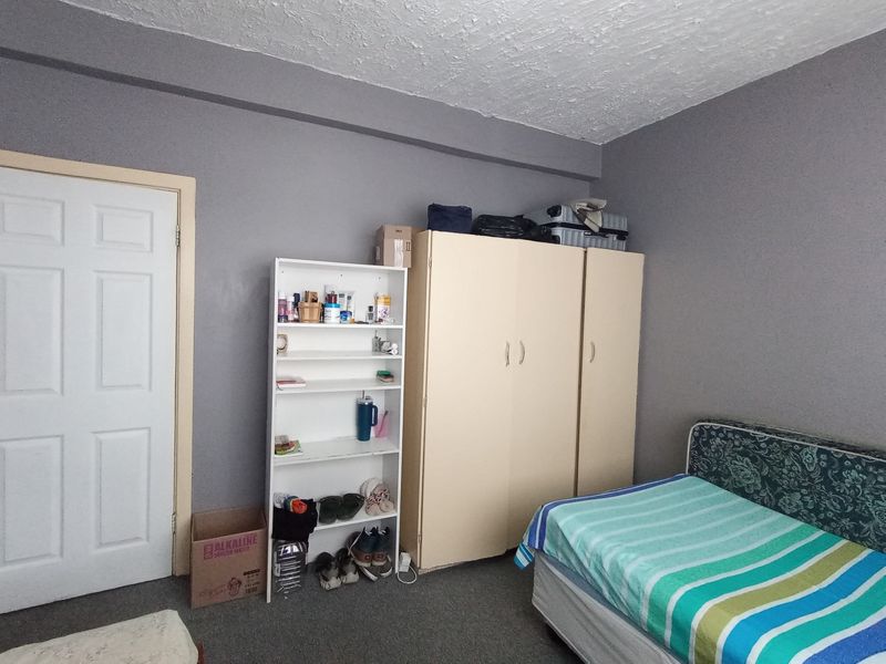 A bedroom featuring a built-in wardrobe and textured ceiling, requiring cosmetic updates to the wall finishes and flooring to enhance its appeal.