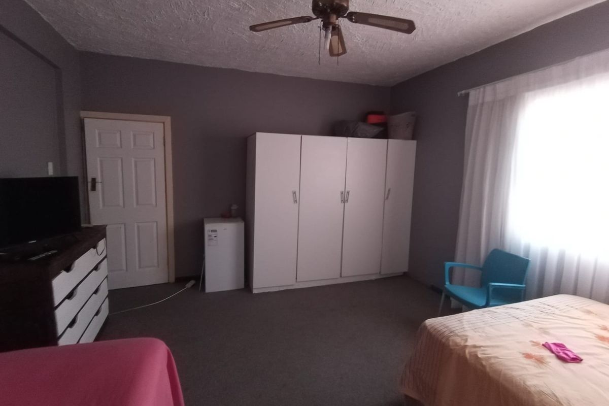 Spacious bedroom featuring a built-in wardrobe, ceiling fan, and carpeted flooring, offering a functional layout with ample natural light.
