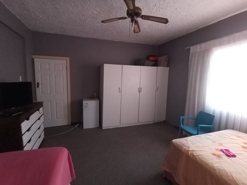 Spacious bedroom featuring a built-in wardrobe, ceiling fan, and carpeted flooring, offering a functional layout with ample natural light.