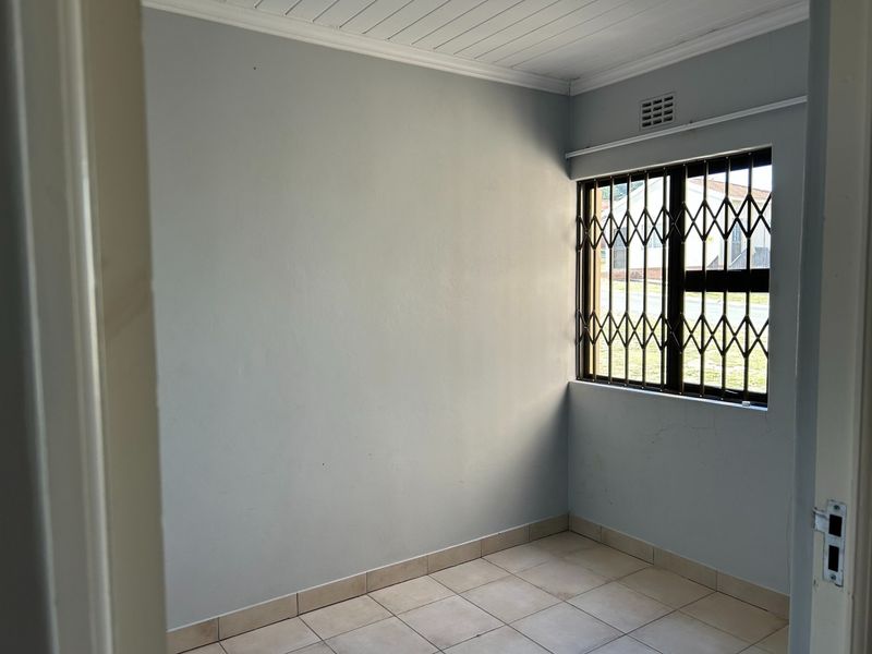 An empty bedroom featuring tiled flooring, a security gate on the window, and neutral wall finishes.
