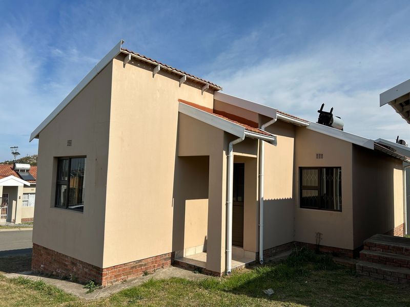 Front view of a single-story residential house featuring a tiled roof, brick plinth, and security bars on the windows.