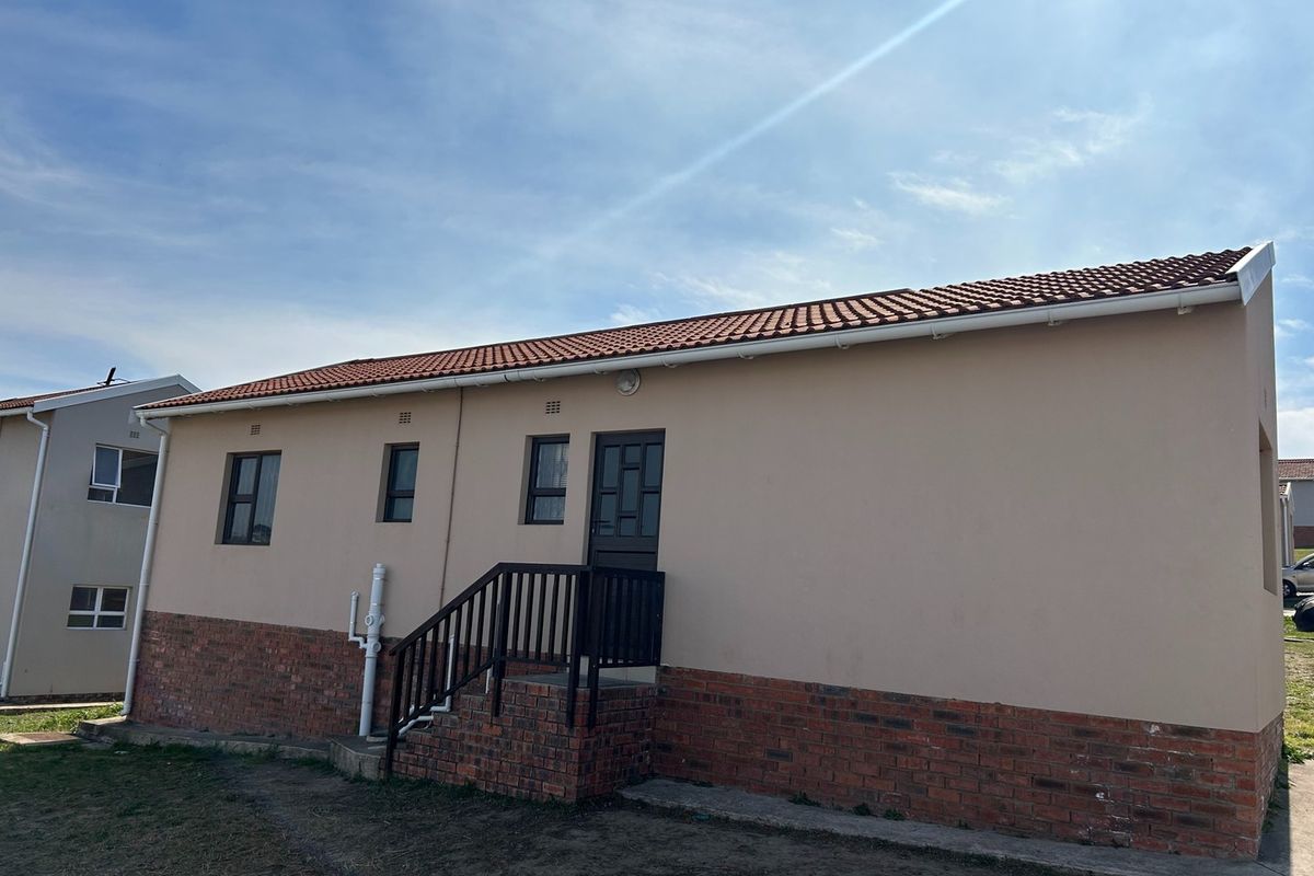 Rear exterior view of a house featuring a terracotta tiled roof, brick base cladding, and an external staircase leading to the entrance.