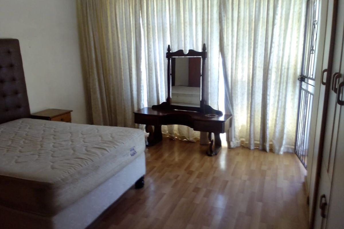 A bedroom featuring laminate flooring, a built-in wardrobe, and a security gate leading to an outdoor area.