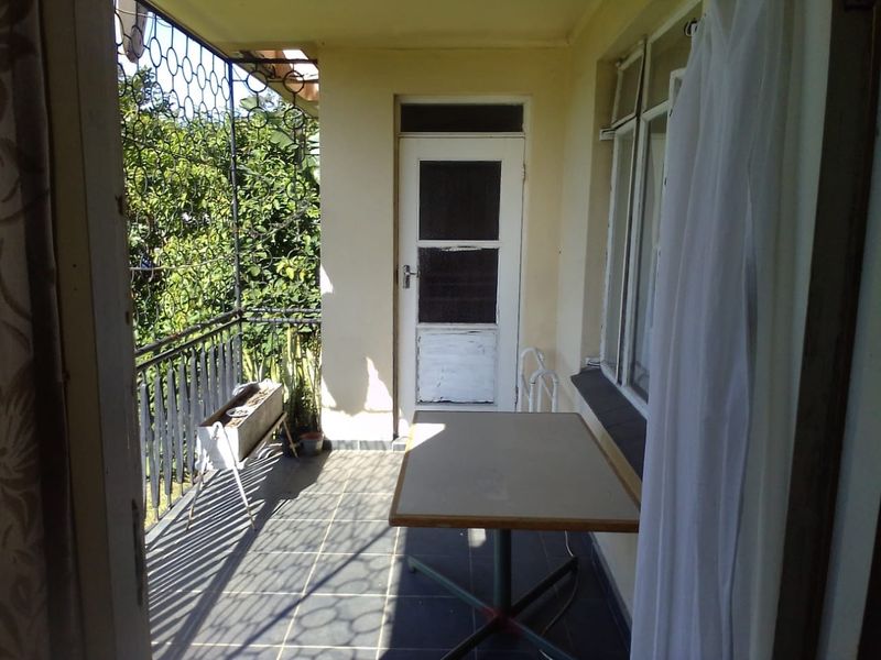 A covered balcony area featuring tiled flooring, a metal security gate, and direct access to the apartment interior.