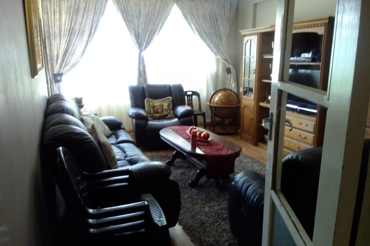 A living room featuring laminate flooring, a timber-framed glass door, and decorative cornice detailing.