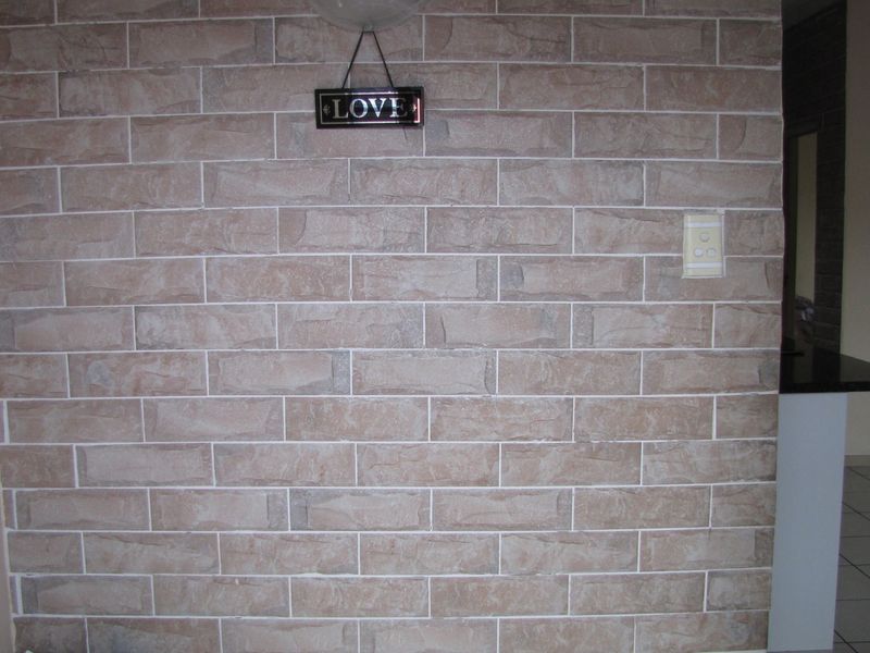An entryway featuring a textured brick-effect feature wall and a timber door, providing a rustic aesthetic to the home's entrance.