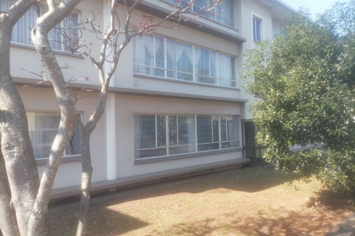 Exterior view of a multi-story apartment building featuring large windows and a landscaped garden area.