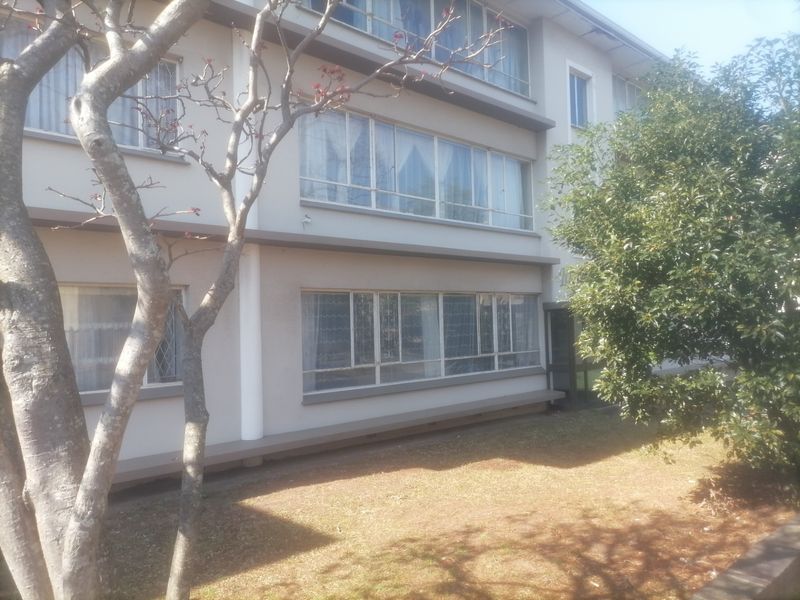 Exterior view of a multi-story apartment building featuring large windows and a landscaped garden area.