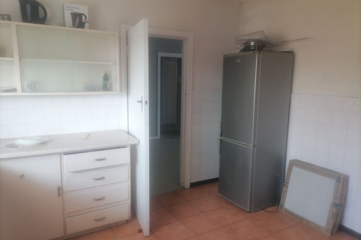 A functional kitchen space featuring built-in cabinetry, tiled splashbacks, and tiled flooring, offering a blank canvas for potential renovation and modernization.