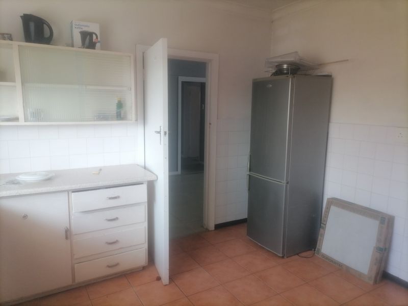A functional kitchen space featuring built-in cabinetry, tiled splashbacks, and tiled flooring, offering a blank canvas for potential renovation and modernization.